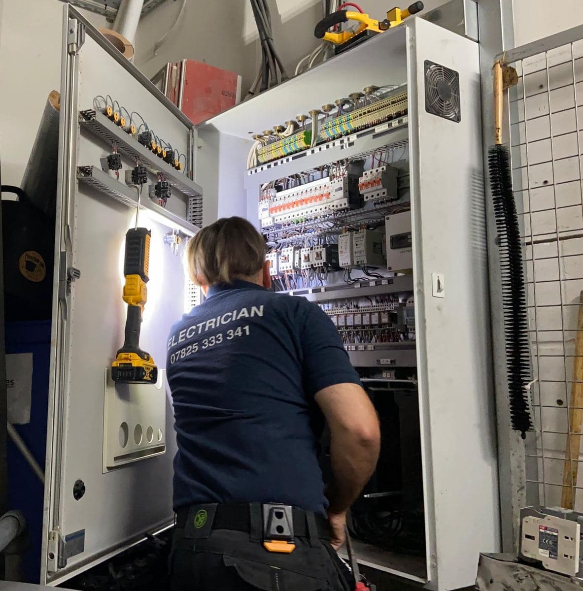 Electrician wiring the contactors and terminals inside a large industrial control panel